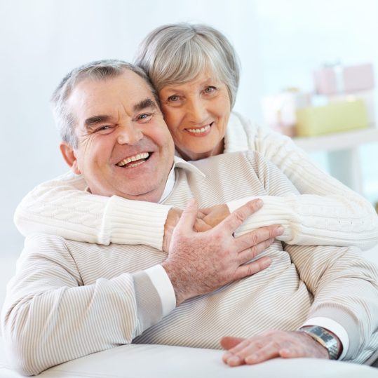 Portrait of a happy senior woman embracing her husband and both looking at camera